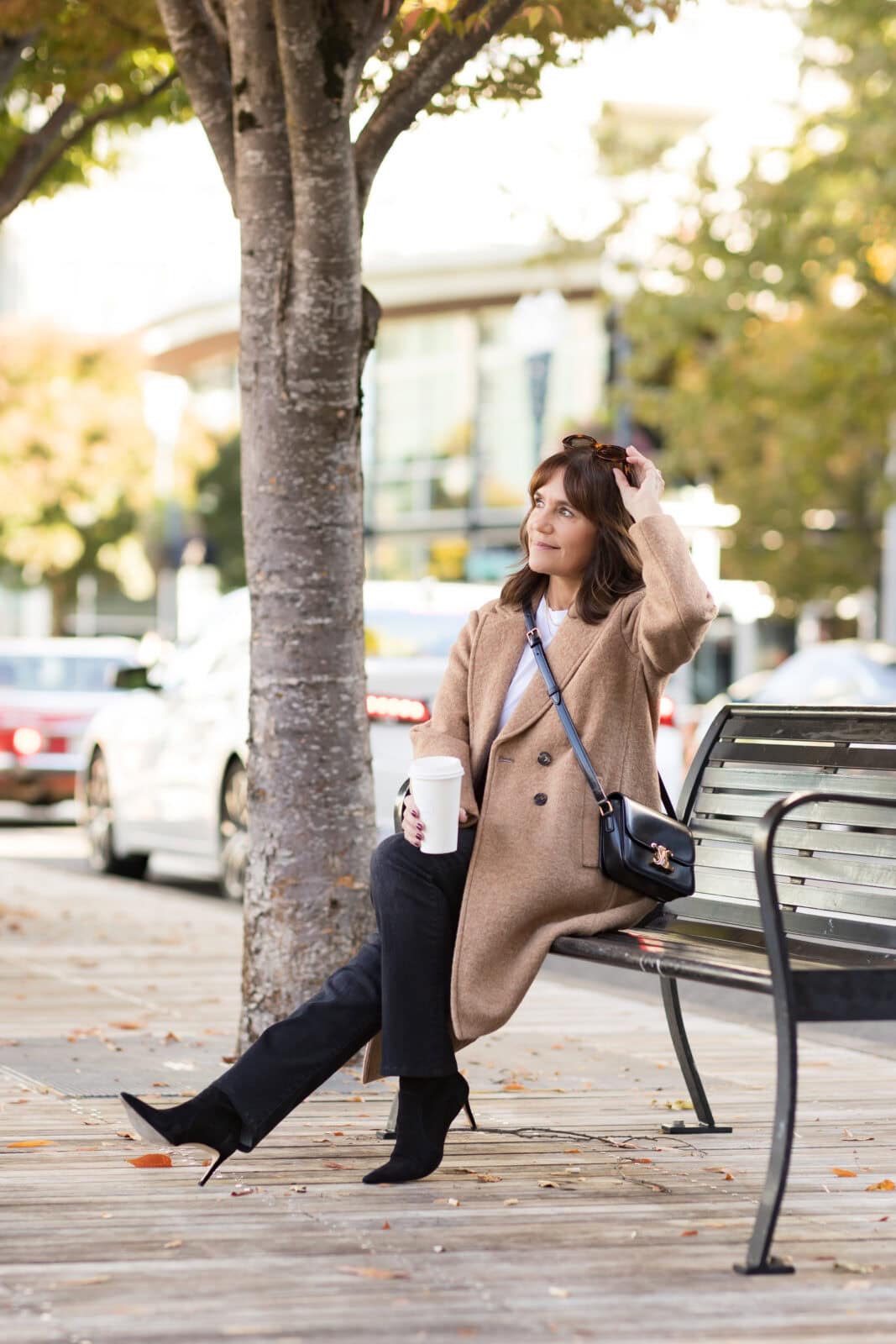 Susie wearing casual fall outfit with tan wool coat, white t-shirt, black jeans, and black boots.