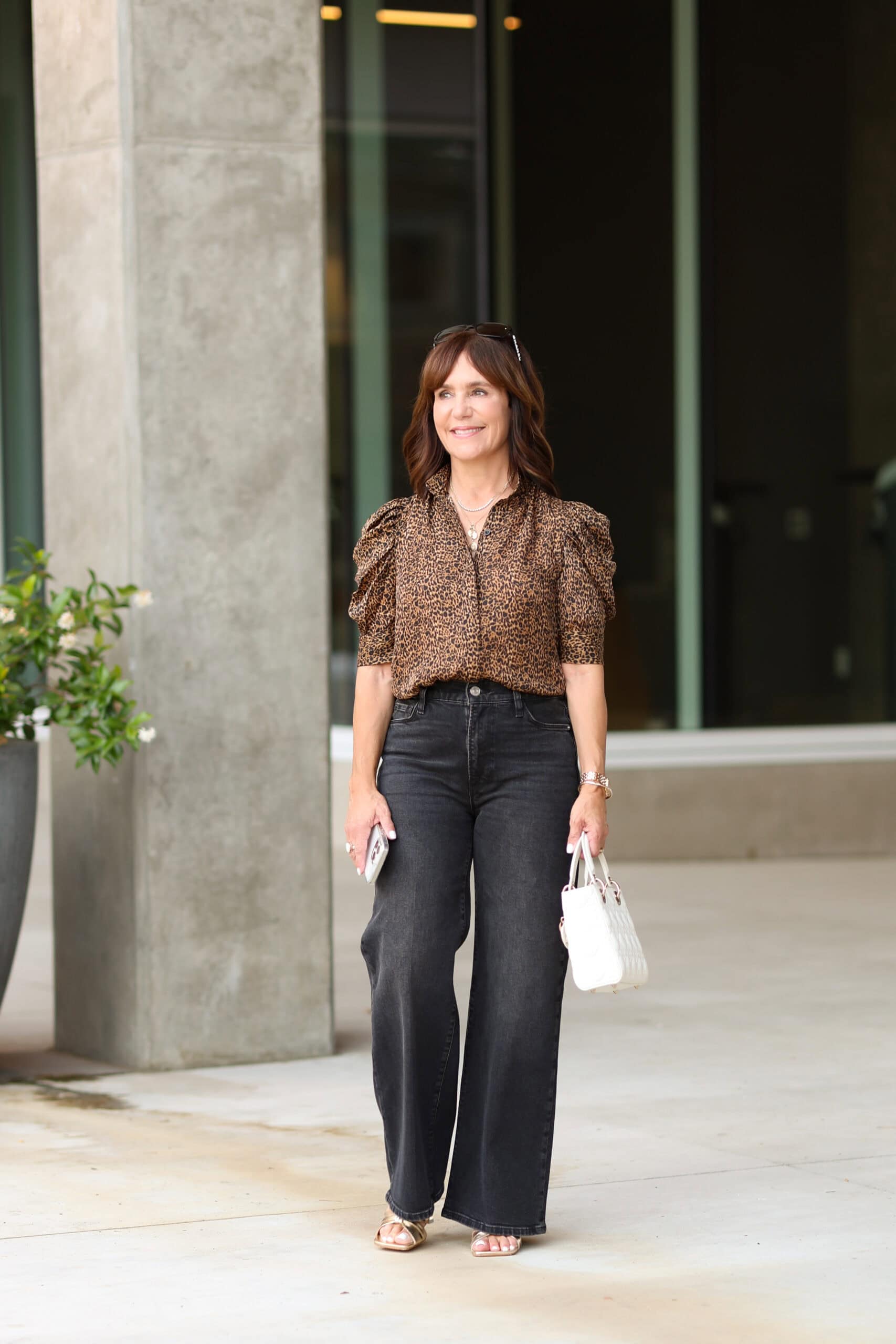 Susie wearing casual fall outfit with leopard print blouse (Frame Gillian) and black white leg jeans with gold sandals. 