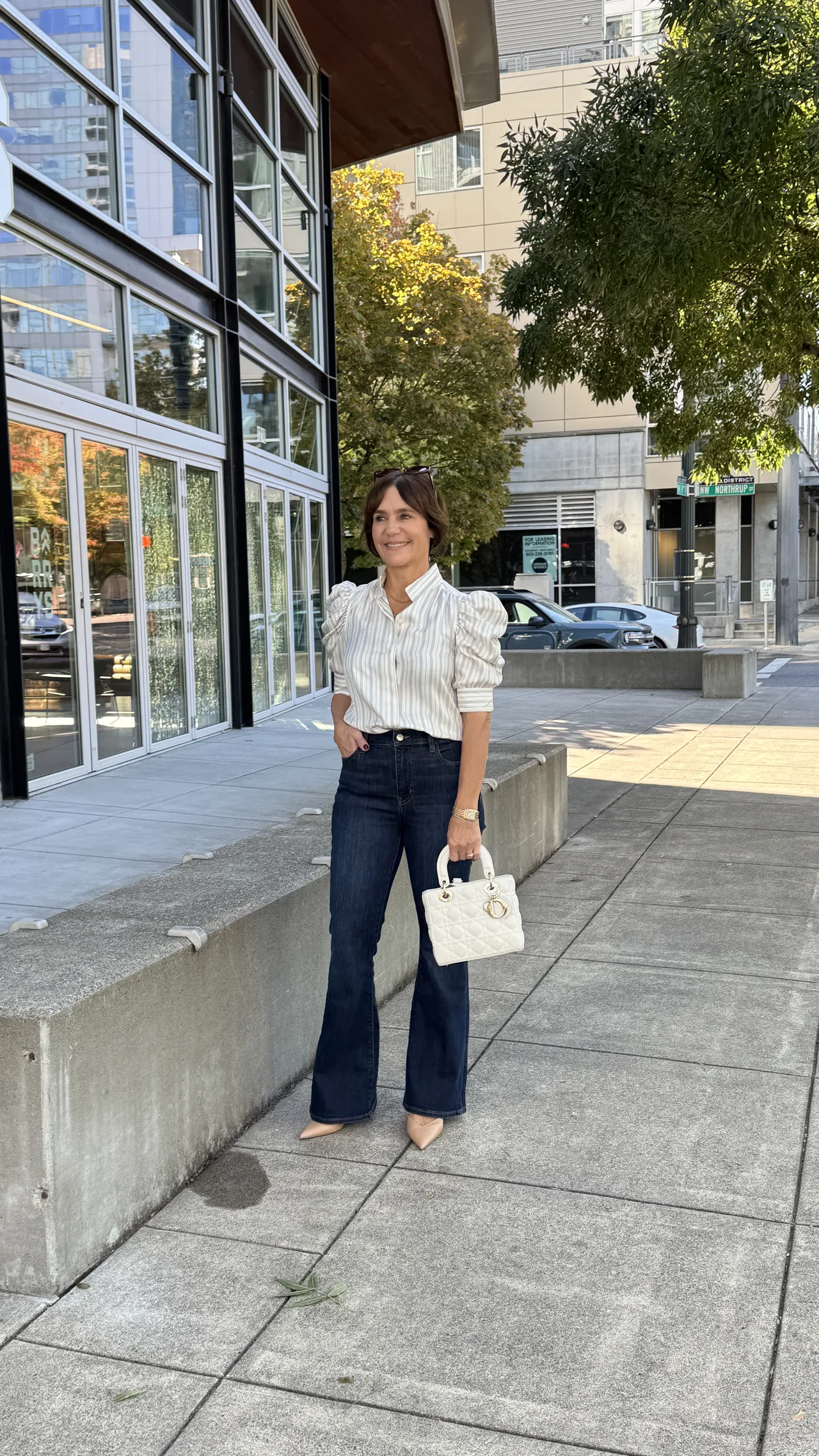 Susie wearing daytime outfit with puff sleeve Frame Gillian blouse, and dark wash flare jeans. 