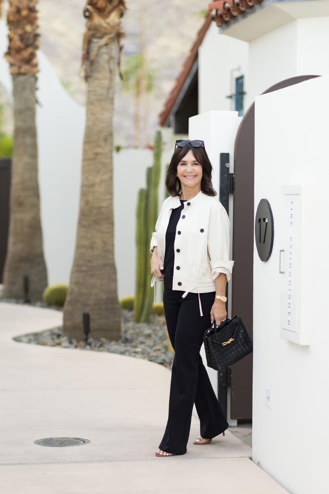 Susie wearing simple spring transition outfit with all black top and jeans, and a utility jacket in Palm Springs.