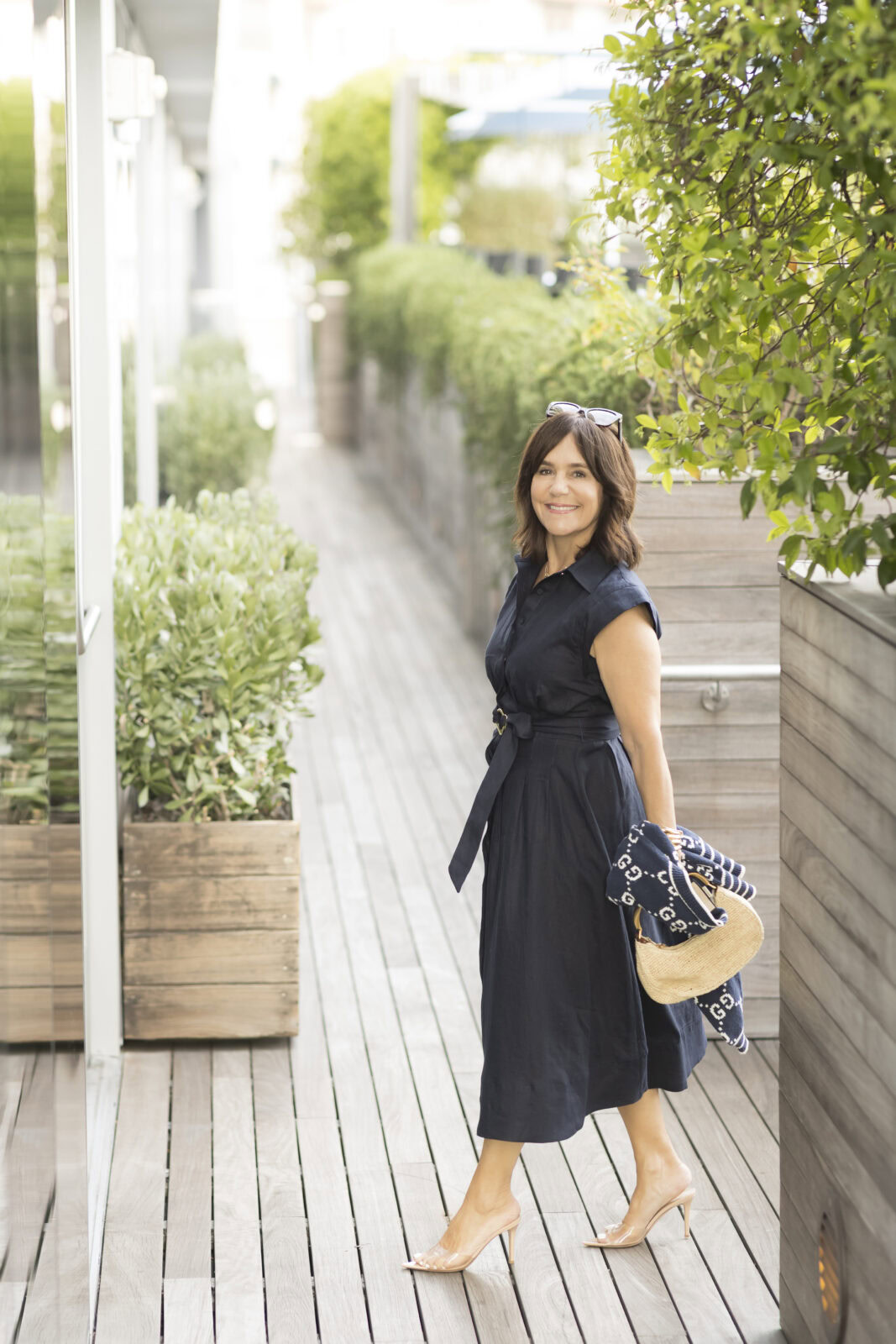Susie wearing a navy linen Veronica Beard dress with a Gucci sweater and raffia bag - a perfect graduation dress outfit